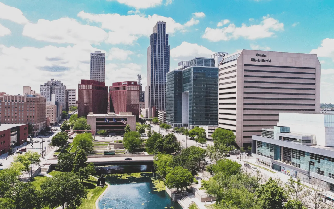 Downtown Omaha skyline above a landscaped riverfront and waterway.