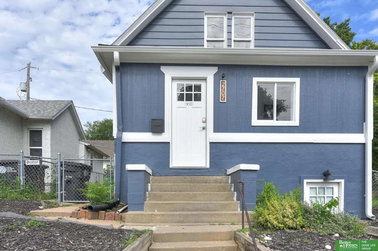 Blue two-story home with white trim, concrete steps, and a centered front entrance.