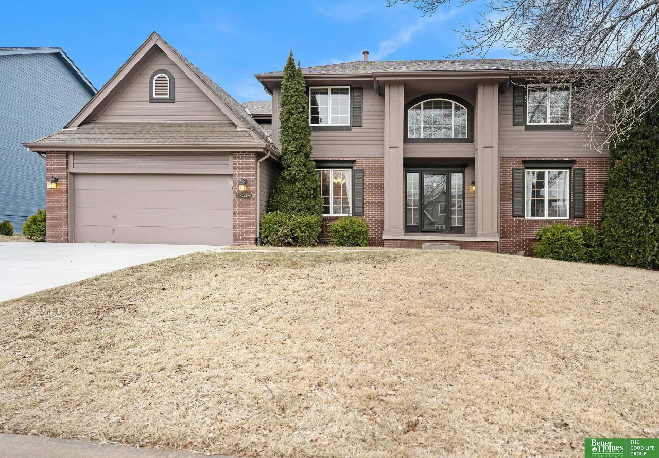 Two-story brick-and-siding home with an attached double garage and dormant front lawn.