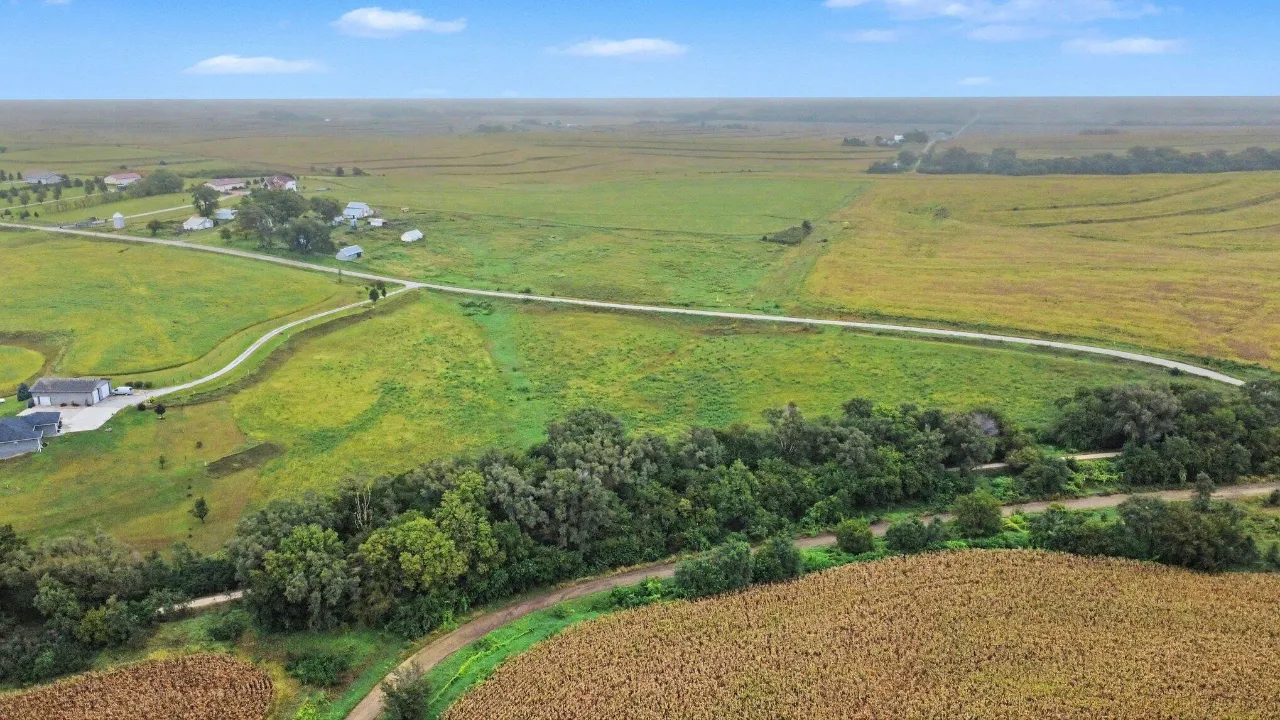 Aerial view of rural farmland with crop fields, open pasture, and a winding road.