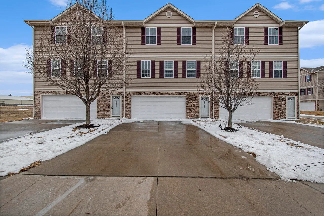 Multi-unit building with stone veneer, attached garages, and snow-covered landscaping.